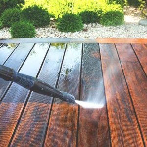 High-pressure hose removing dirt from a stained deck